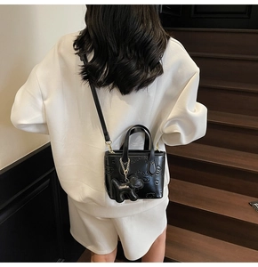 Détail d'un sac seau noir avec motif de chien gaufré et joli pendentif chiot 3D