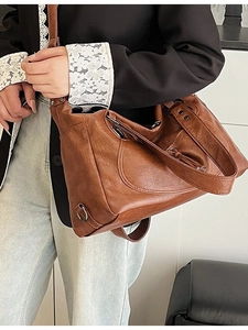 Brown leather tote bag featuring a motorcycle style design with silver metal rings and straps
