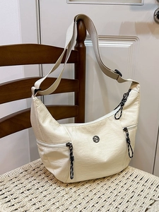 Sac dumpling minimaliste blanc crème suspendu à une chaise en bois rustique