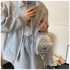 Detail of silver quilted mini backpack with metallic twist lock and chain strap