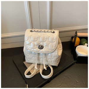 Macro detail of white star-quilted mini backpack with silver metal twist lock closure