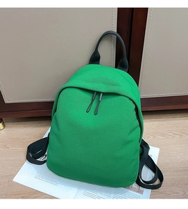 Detail of a bright green Oxford cloth backpack with black zipper and woven texture fabric