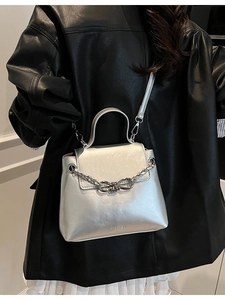 Chic silver crossbody flap bag with metallic chain and knot detail on model