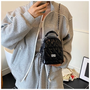 Detail of glossy black quilted mini backpack with silver metal chain and twist lock