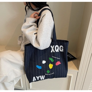 Detailed view of striped canvas tote bag with bold lettering and colorful graffiti accents