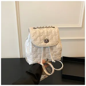 Close-up of white star-quilted PU leather backpack with chain handle and metal twist lock