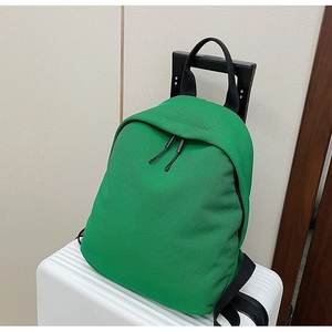 Green oxford fabric backpack with honeycomb mesh texture placed on a white suitcase