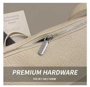 Detailed macro view of silver metal zipper and textured leather on cream shoulder bag