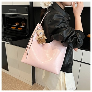 Detail of light pink tote bag with shiny leather texture and cute bear charm in kitchen