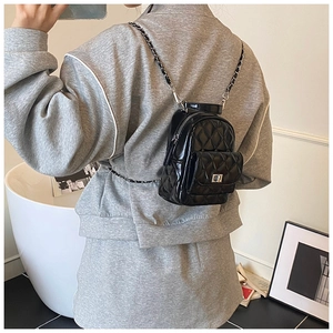 Detail of black quilted mini backpack with silver chain strap and shiny patent finish