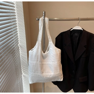 Detailed view of the textured white canvas tote bag hanging in a minimalist setting
