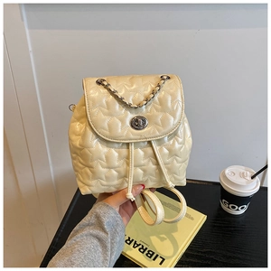 Detail showing cream quilted backpack with star pattern and silver chain handle