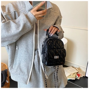Close-up of black quilted leather backpack with silver turn-lock and chain strap detail