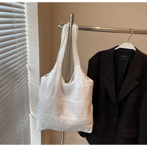 Detail of white tote bag with unique pleated texture hanging in a minimalist setting