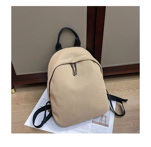 Macro detail of the beige woven texture and black fabric strap on the mini backpack