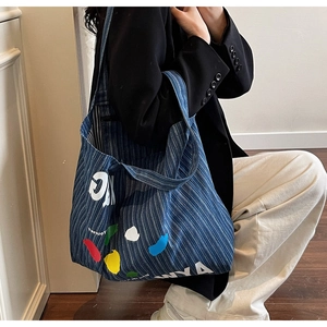 Blue striped denim tote bag featuring colorful paint splatter and large white letters