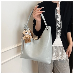 Close-up of light blue leather tote bag with brown plush bear charm detail