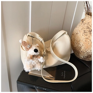 Detail der cremefarbenen Ledertasche mit Lychee-Narbe und niedlichem Plüsch-Hundeanhänger