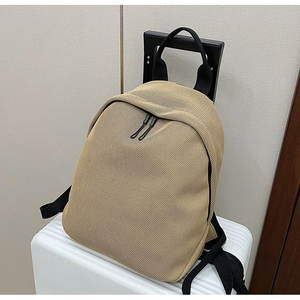 Close-up of khaki mesh backpack hanging on white suitcase handle for travel convenience