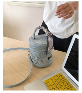 Dettaglio macro di borsa a secchiello azzurra con graffiti e manico in foulard di seta
