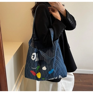 Detail of blue striped canvas tote bag with abstract paint design and shoulder straps
