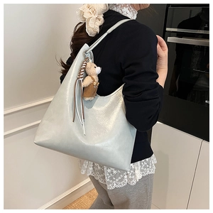 Detail of grey-blue leather tote bag with glossy finish and cute brown bear pendant