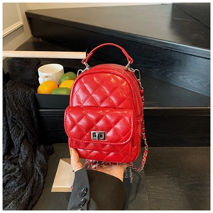Detail of red quilted mini backpack featuring metallic chain strap and twist lock