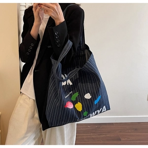 Detail of a large denim tote bag featuring stylish stripes and colorful WYA graphic prints