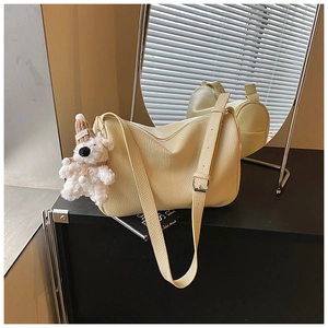 Detail der cremeweißen Ledertasche mit süßem Plüschbär-Anhänger und verstellbarem Riemen