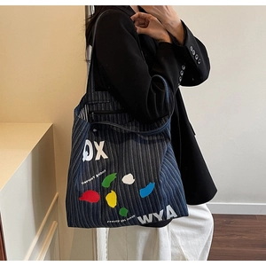 Detail shot of striped denim tote bag showing inner pocket and colorful graffiti print