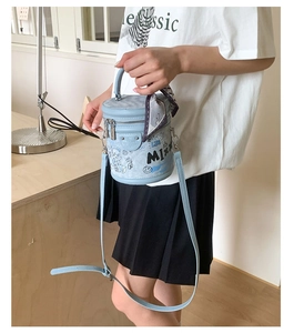 Dettaglio borsa a secchiello azzurra con stampe graffiti e foulard di seta viola decorativo