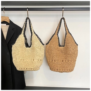 Detailed view of handmade straw woven tote bags in beige and light brown with black trim