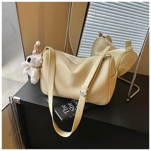 Nahaufnahme der cremefarbenen Leder-Achseltasche mit Plüschhund-Anhänger und Silber-Schnalle