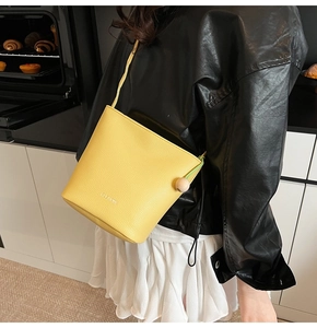 Detail of yellow lychee leather bucket bag with wooden bead accent on the shoulder strap