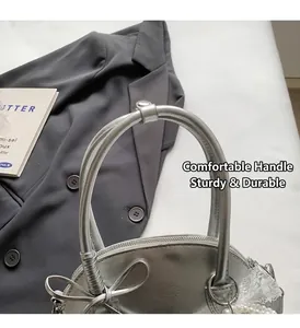 Dettaglio borsa a mano argento con fiocco, ciondolo in pizzo perlato e zip superiore