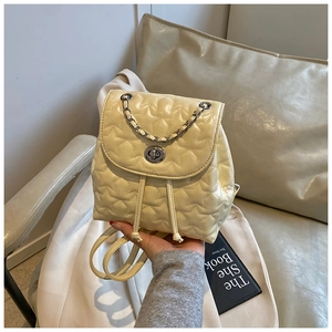 Close-up of cream quilted leather mini backpack with star patterns and silver twist lock