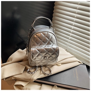 Detail of silver quilted mini backpack with metallic finish and metal turn-lock closure