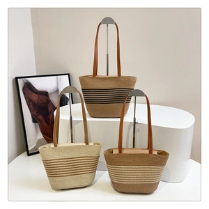 Detailed view of woven straw tote bags in various striped colors with long leather straps