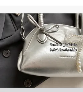 Dettaglio borsa a conchiglia argento con catena di perle, fiocco in pizzo e pelle metallica