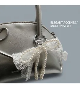 Dettaglio borsa in pelle argento con fiocco in pizzo di perle e scritte alla moda