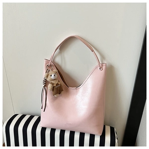 Detail of light pink patent leather shoulder bag with a cute bear plush keychain