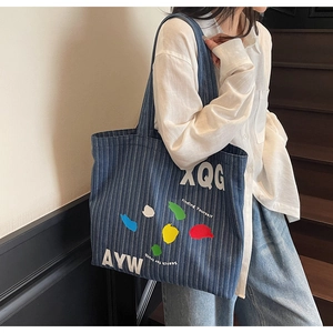 Detail of blue striped canvas tote bag with street style lettering and artistic graphics