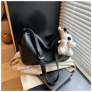 Schwarze Schultertasche aus genarbtem Leder mit niedlichem Plüschbär-Anhänger im Detail