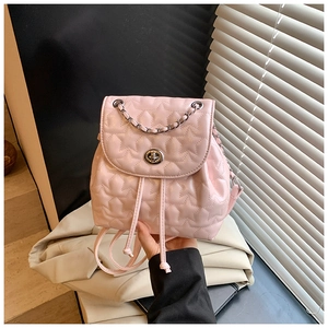 Pink quilted backpack with star pattern stitching and silver chain detail held by hand