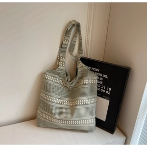Close-up of green and white checkered canvas tote bag with woven texture on white wall