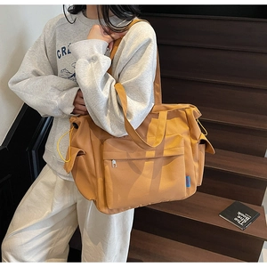 Detail of a large yellow tote bag with side drawstrings and multiple front zip pockets