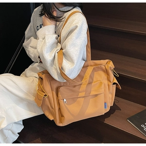 Detail of large khaki tote bag showing side pockets and yellow drawstring on durable fabric