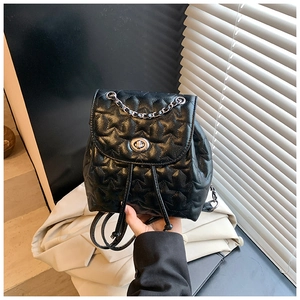 Detail of black quilted star pattern on backpack with silver twist lock and metal chain