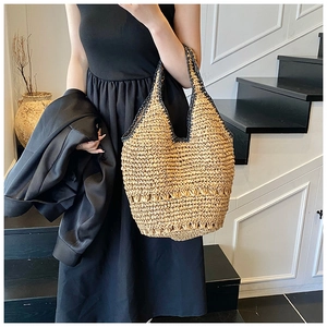 Detail of straw woven tote bag with hollow design on a woman in black dress