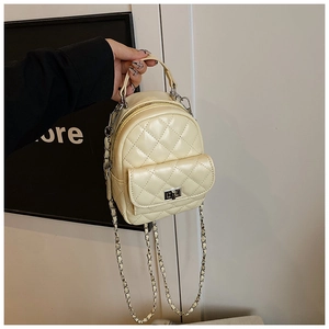 Detail of beige quilted mini backpack with metal chain strap and turn-lock pocket